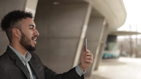 Side-view-of-smiling-young-man-talking-on-smartphone